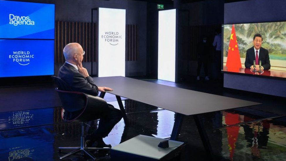 Executive Chairman of the World Economic Forum (WEF) Klaus Schwab listen Chinese President Xi Jinping seen on the TV screen speaking remotely at the opening of the WEF Davos Agenda virtual sessions.