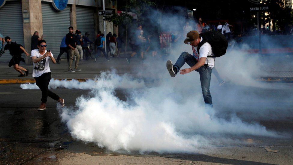A demonstrator kicks a tear gas canister during a protest against the increase in the subway ticket prices in Santiago