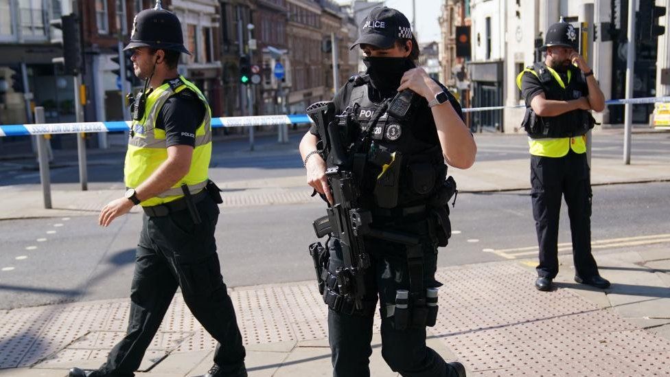 An armed officer and two unarmed police officers on patrol in Nottingham.