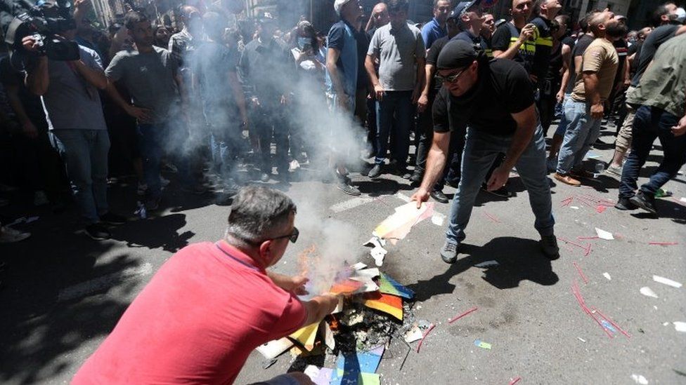 Protesters burn the rainbow flag during a protest in Georgia