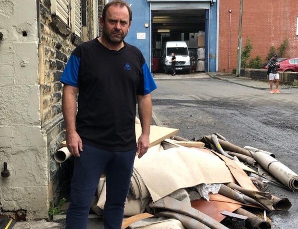 Carpet shop owner Philip Holt with carpet ruined by flood water