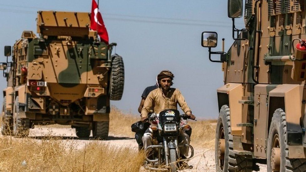 Turkish military vehicles drive on a patrol in the Syrian village of al-Hashisha on the outskirts of Tal Abyad