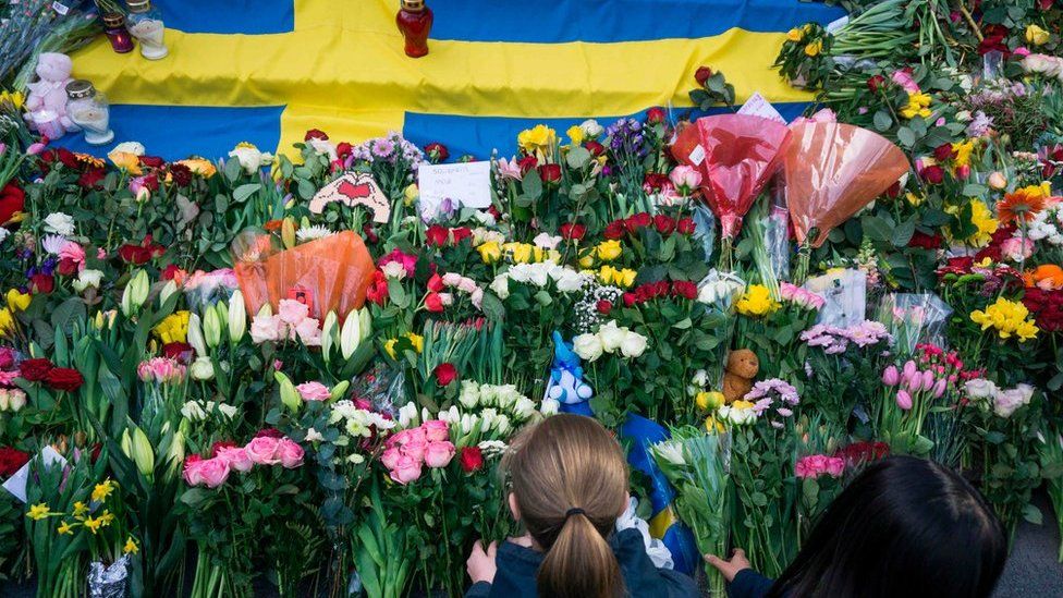 Women lay flowers on April 9, 2017 at a makeshift memorial near the point where a truck drove into a department store in Stockholm, Sweden