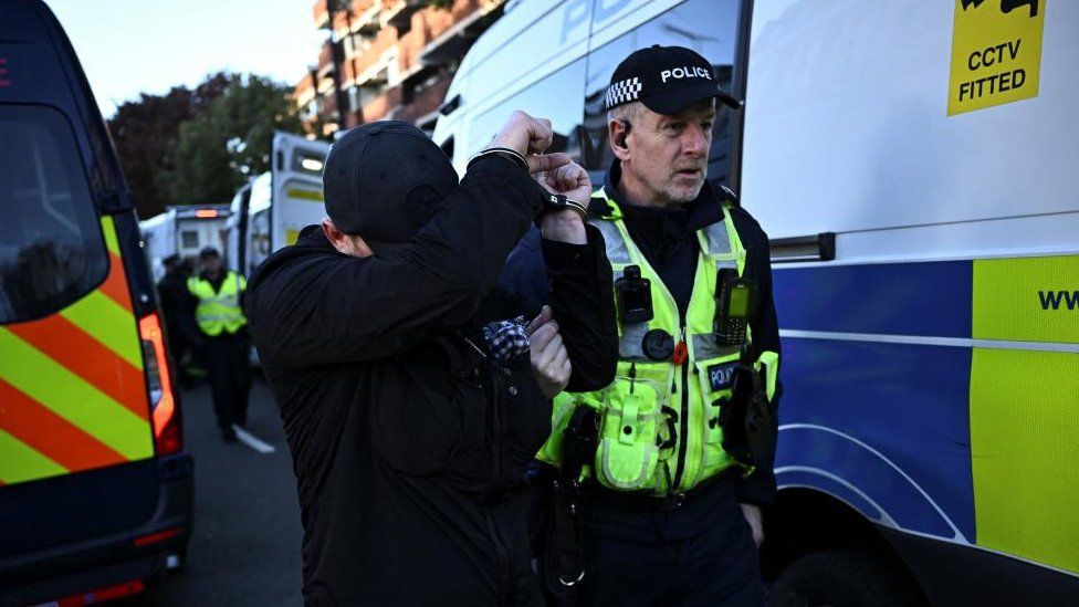 A counter-protestor, handcuffed, arrested by a police officer, London