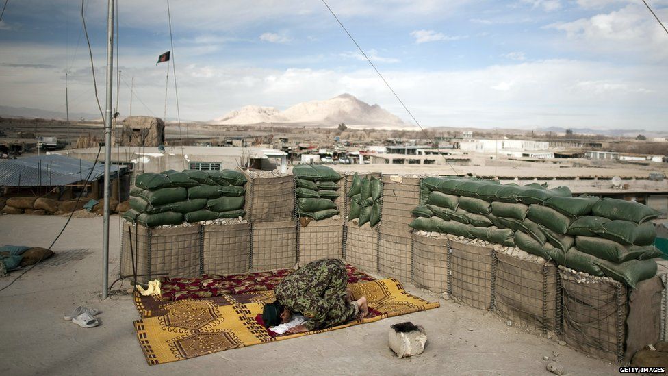 An Afghan National Army (ANA) soldier prays on the rooftop of the Musa Qala District centre base in Helmand province