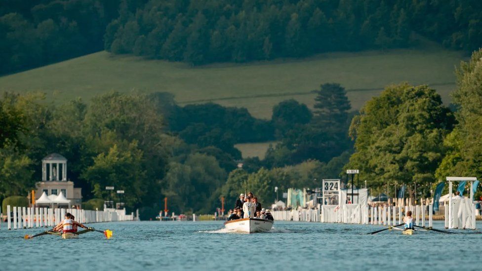 Two rowing teams racing on the River Thames either side of an umpire boat
