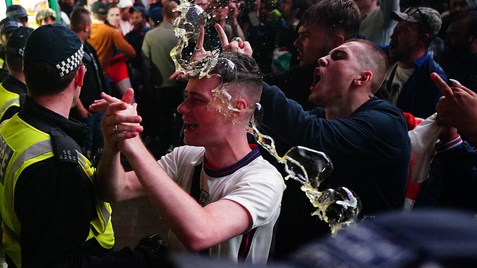A fan is covered in a drink thrown at a police line in central London