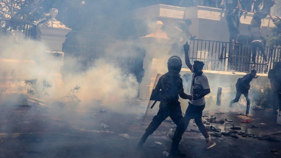 Силы безопасности применяют слезоточивый газ для разгона демонстрантов, пытающихся проникнуть в офис премьер-министра в Коломбо, Шри-Ланка, 13 июля 2022 г.