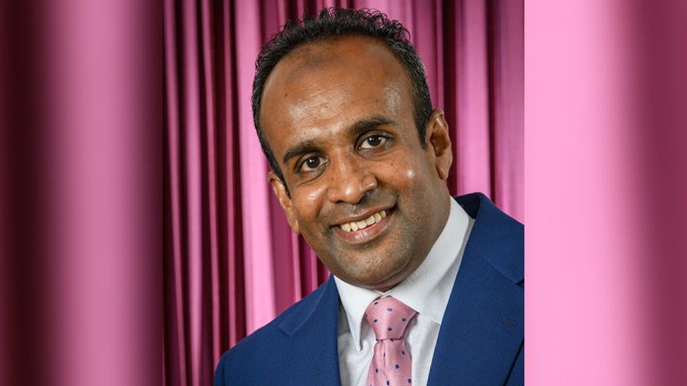 Head and shoulders image of Atiqul Hoque wearing a blue jacket and pink tie