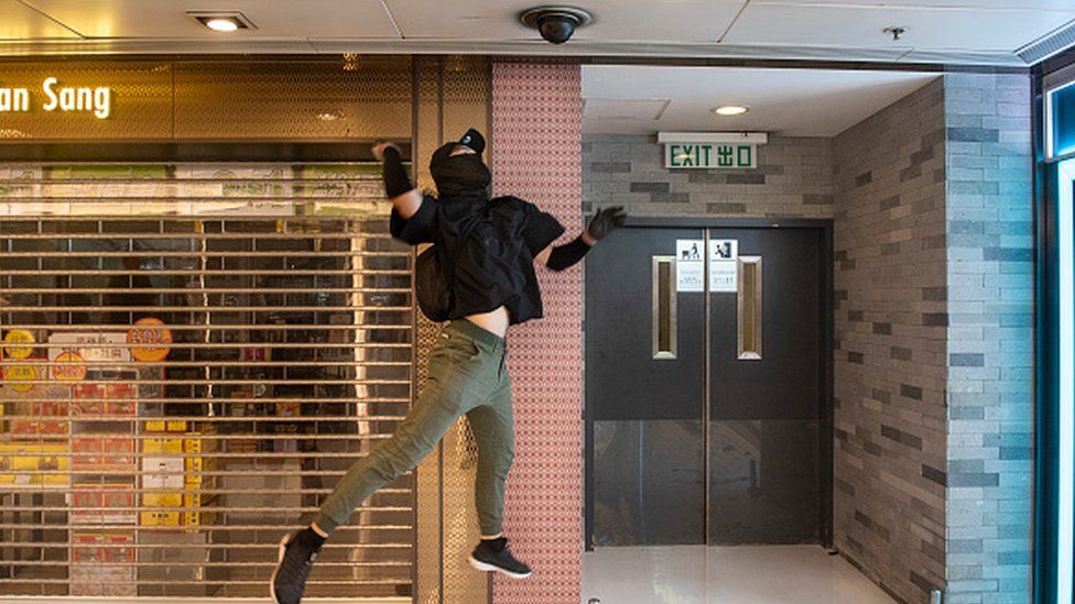 ГОНКОНГ, КИТАЙ - 2019/10/13: протестующий прыгает и разбивает камеру наблюдения в торговом центре New Town Plaza во время демонстрации.