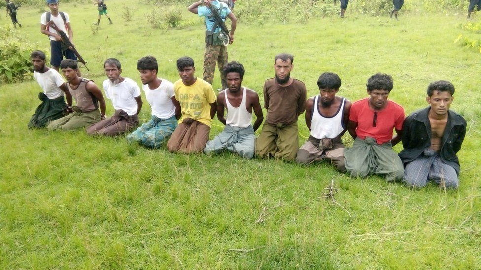 Ten Rohingya Muslim men with their hands bound kneel as members of the Myanmar security forces stand guard in Inn Din village, taken Sept 2017
