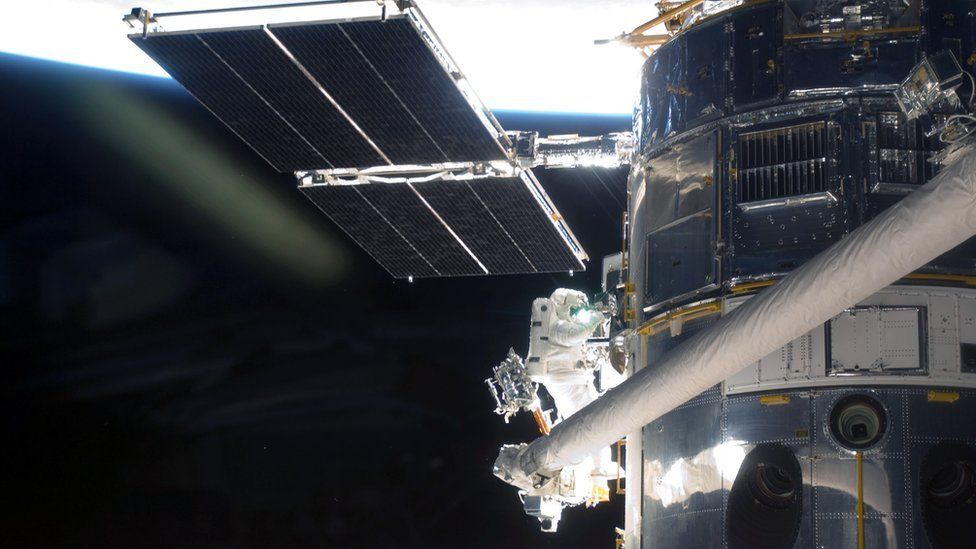An astronaut works on the Hubble telescope