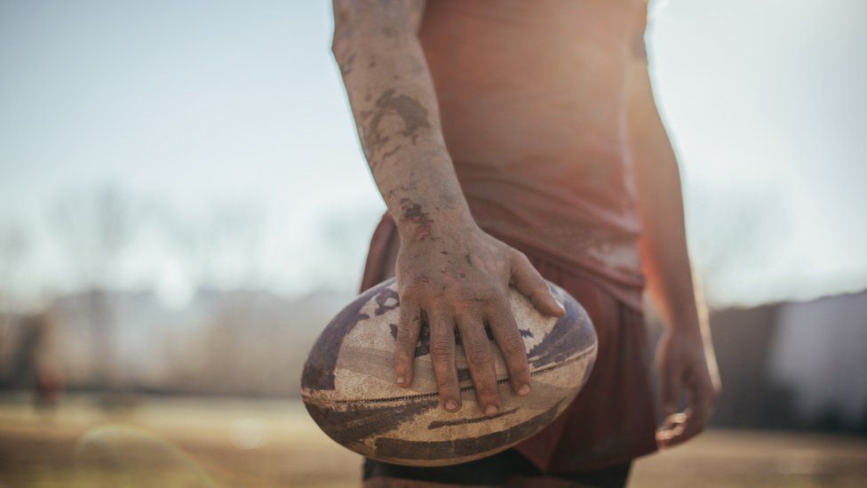 A rugby player holding a rugby ball