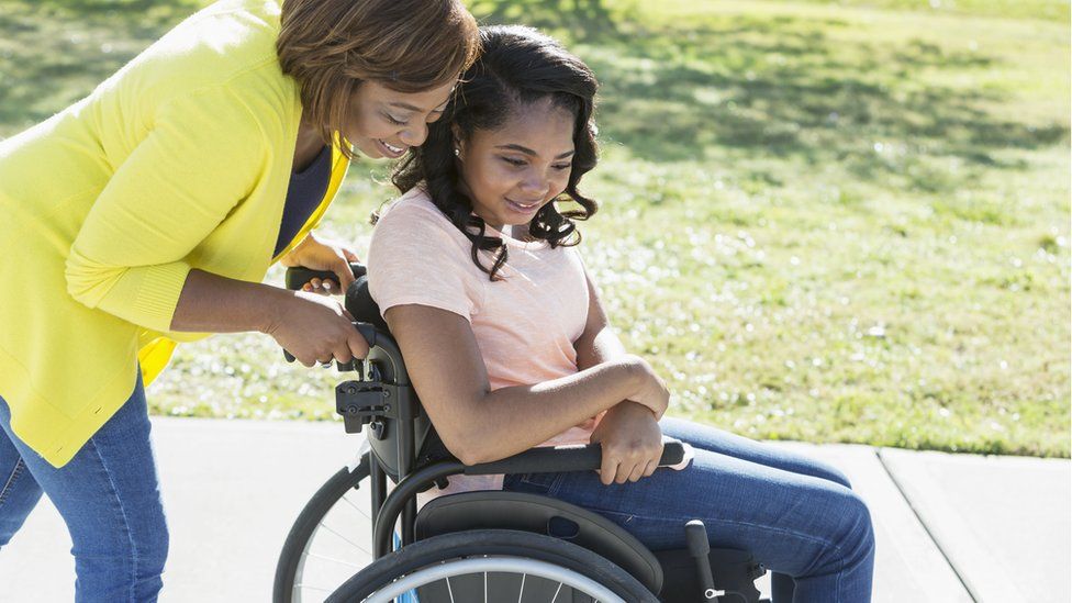 A mother pushing her wheelchair-bound daughter