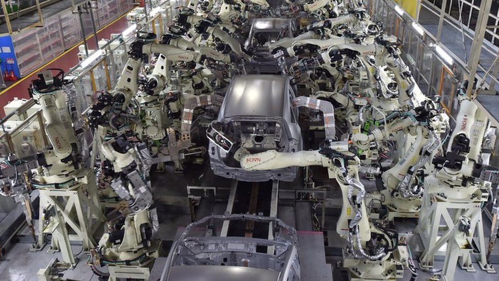 Robots welding car bodies in factory