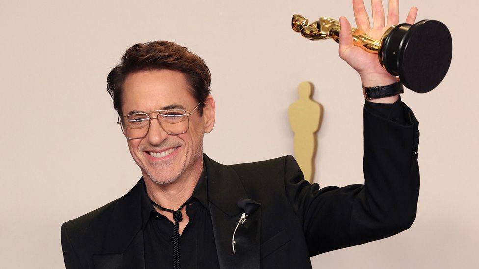 Robert Downey Jr holding up his Oscar