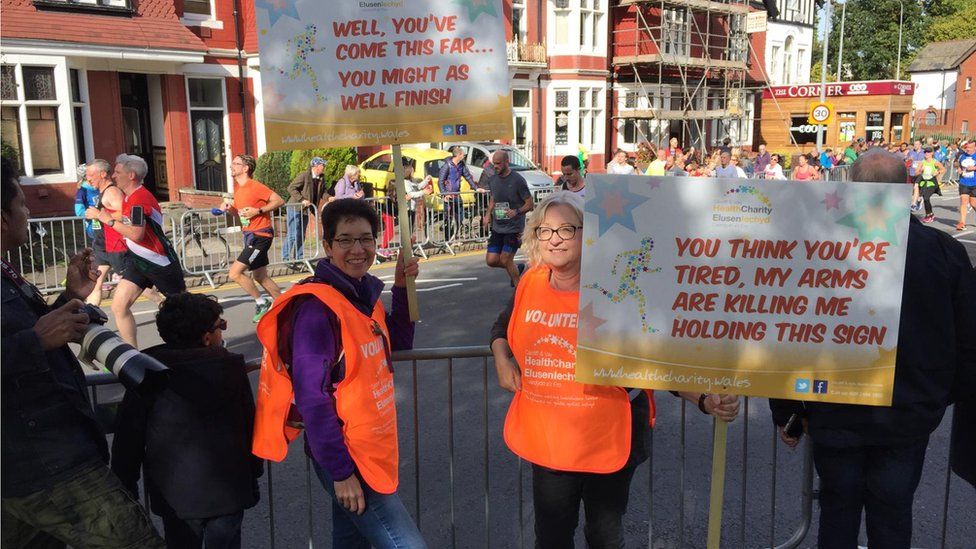 Two women hold signs