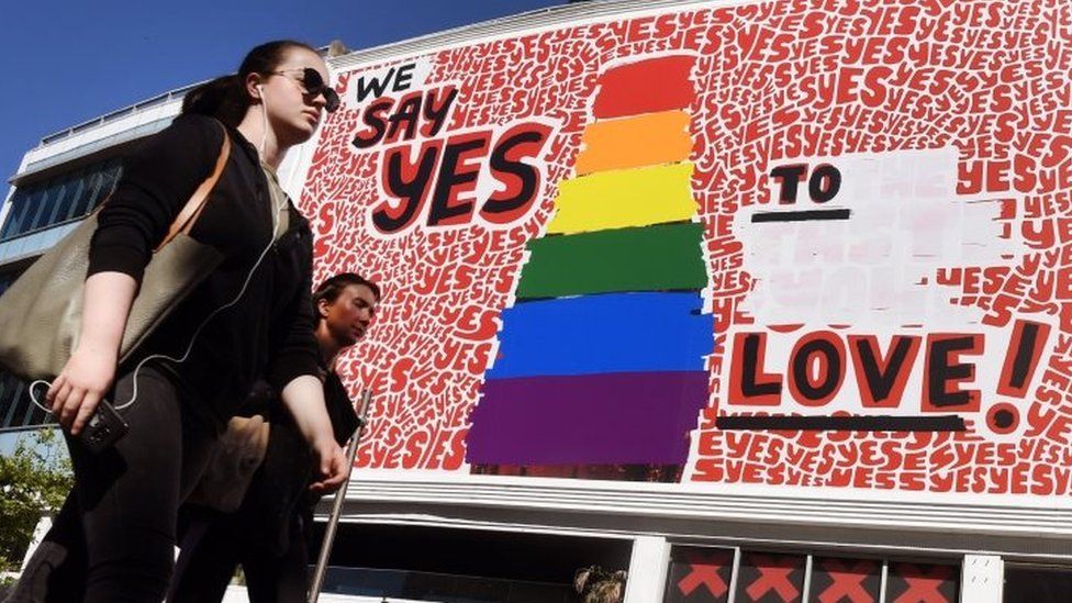People walk past a giant billboard promoting the "yes" vote for same-sex marriage in Sydney's Kings Cross district (14 November 2017)