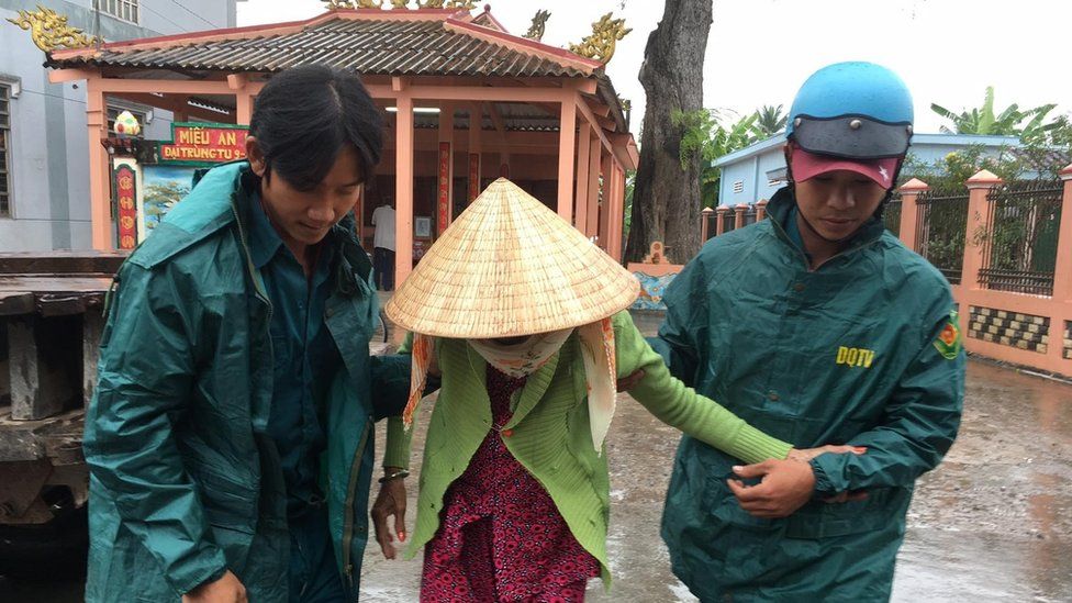 Municipal workers evacuate a local woman as Typhoon Tembin approaches in Ben Tre, Vietnam, 25 December