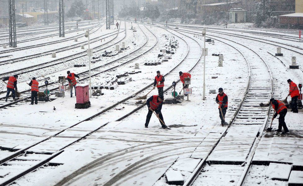 Workers clear snow on the rails at a railway station in Jiujiang in central China's Jiangxi province 21 January 2016