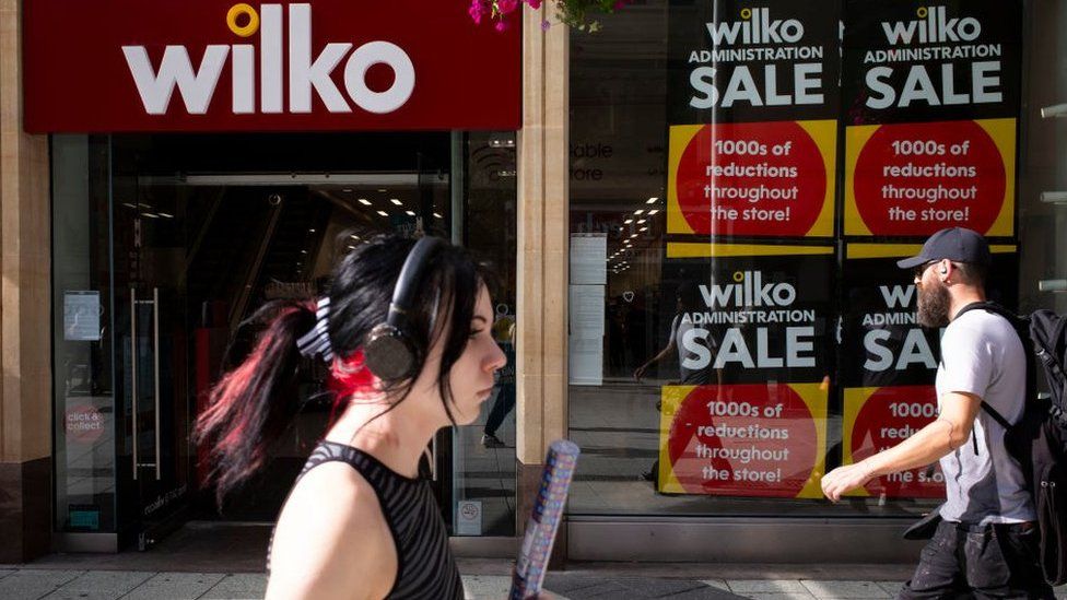 Женщина проходит мимо витрины магазина Wilko