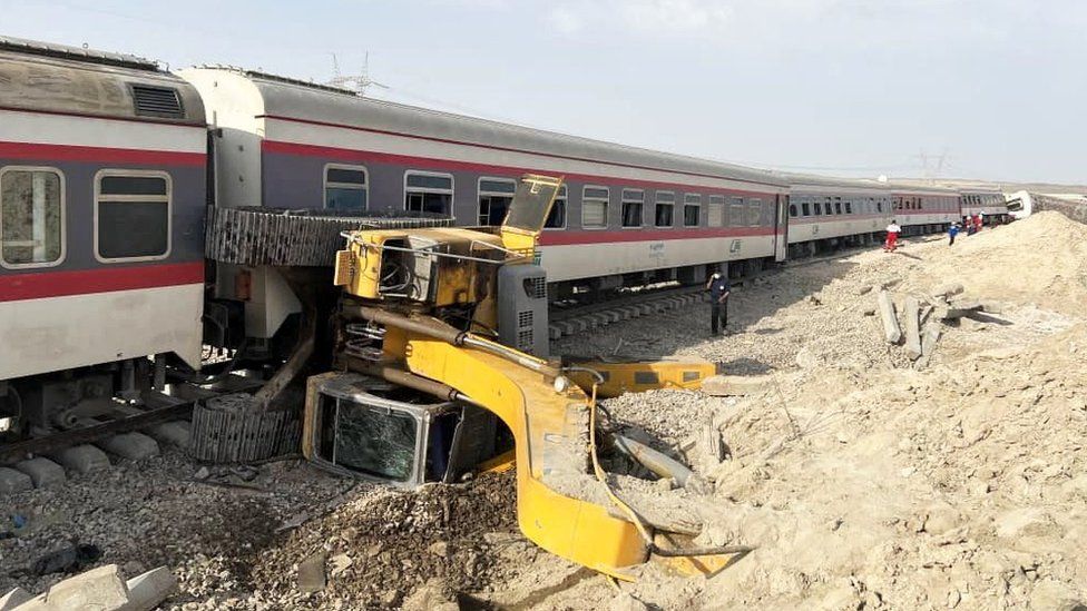 Yellow excavator on its side by the track after a train derailment in eastern Iran (8 June 2022)