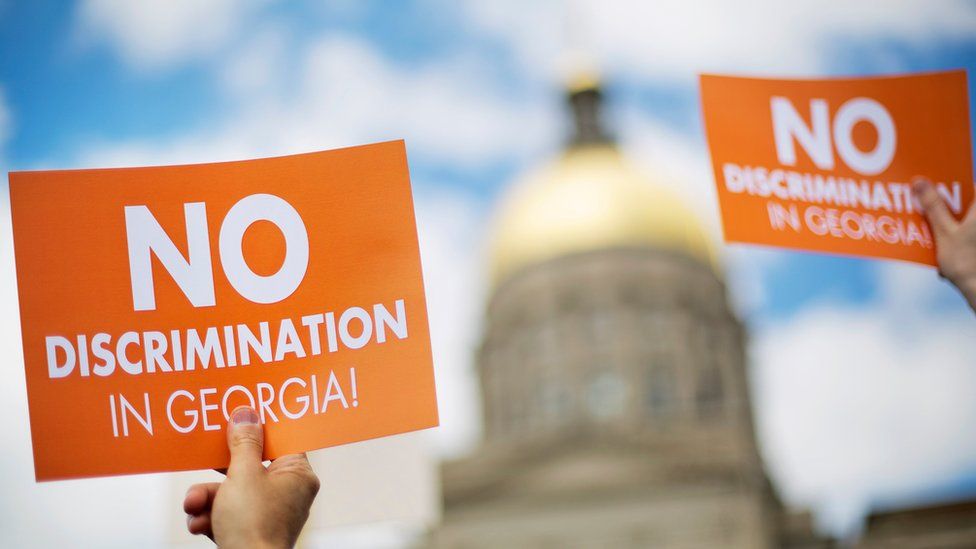 Protesters hold up signs as the dome of the Capitol stands in the background during a rally against a contentious "religious freedom" bill in Atlanta