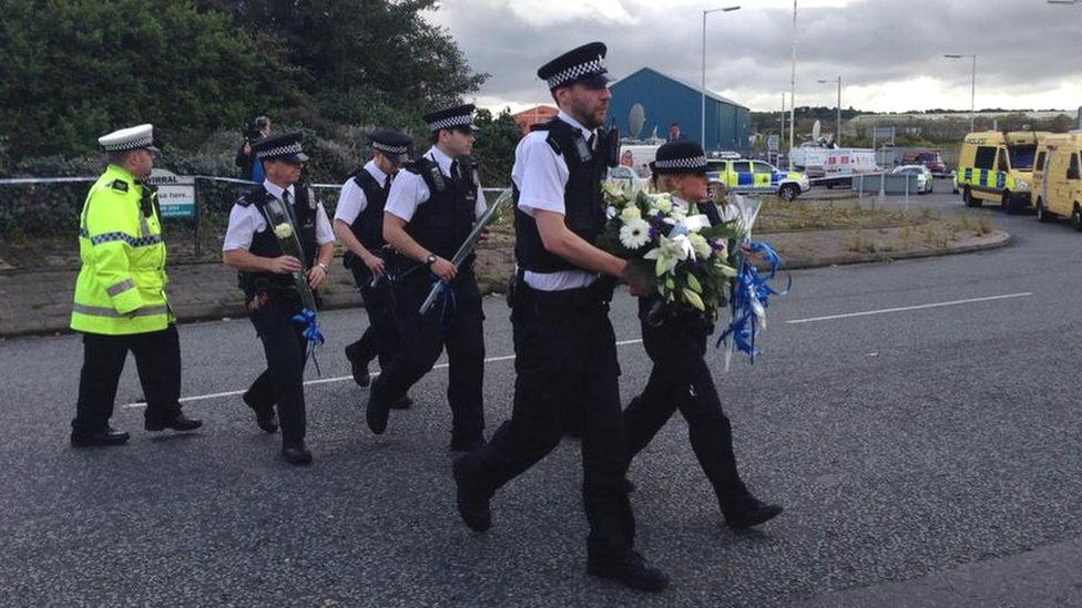 Officers from Wallasey police station lay flowers at the scene