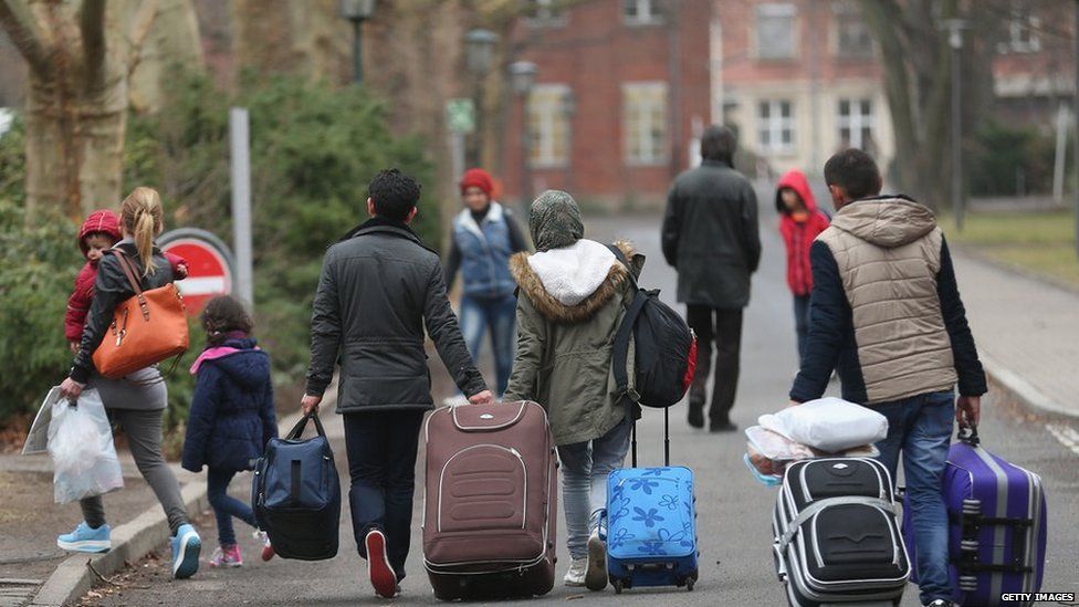 Migrants pulling suitcases outside an asylum registration office in Germany