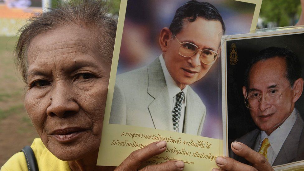 A woman holds up images of Thailand's King Bhumibol Adulyadej to celebrate the 70th anniversary of his reign in Bangkok (9 June 2016)