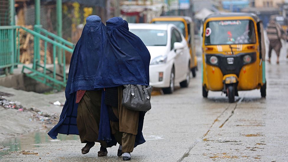 women walking down a street wearing burkas