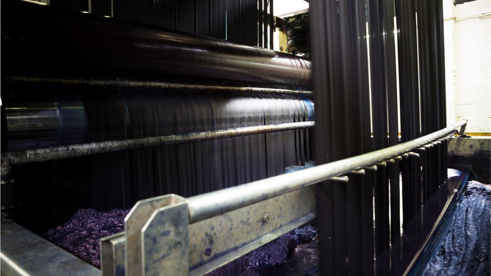 Denim threads are dipped into indigo baths in a rope dying machine at a jeans factory