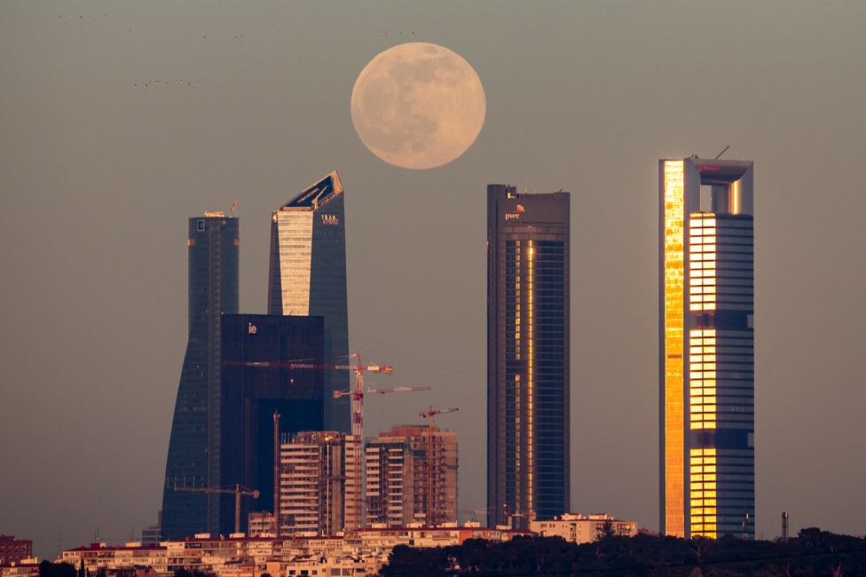 The full Moon rises over the skyscrapers of the Four Towers Business Area of Madrid