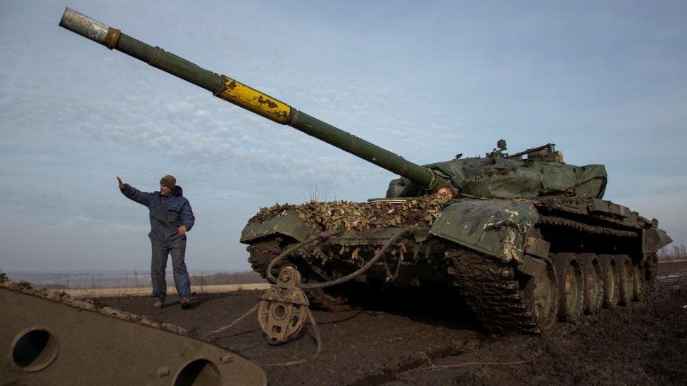A Ukrainian soldier pulls a broken tank to a truck