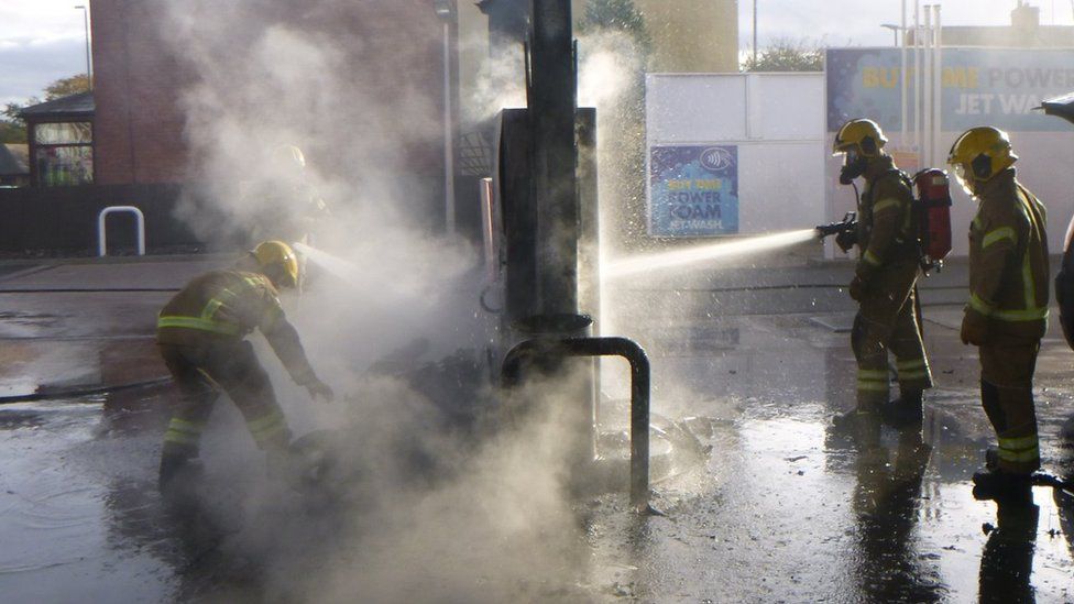 Firefighters spray water on a burning pump