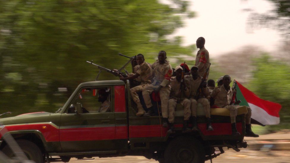 Rapid Support Forces militia are seen driving along the road, holding guns