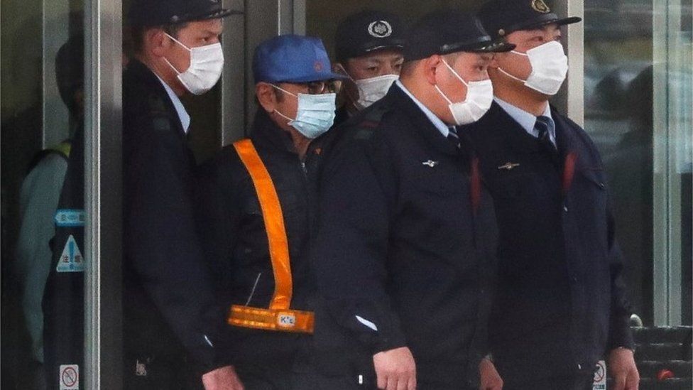 Carlos Ghosn (in the blue hat) leaving prison