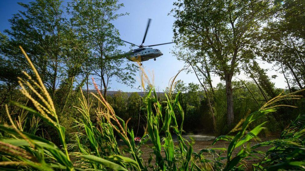 Вертолет набирает воду из пруда.