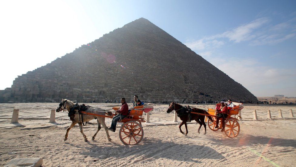 Image shows tourists in front of the Giza pyramids in Egypt