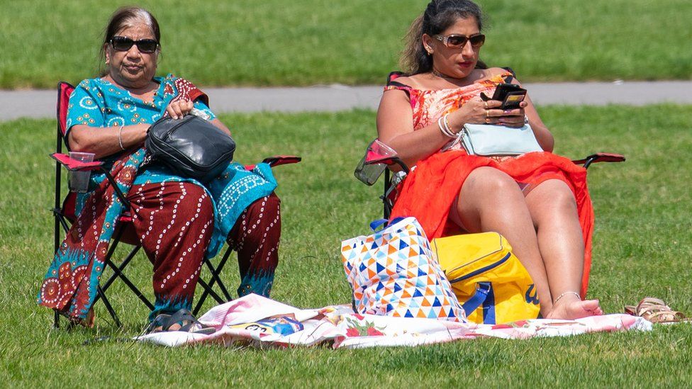 People picnic in the sun in Greenwich Park, London