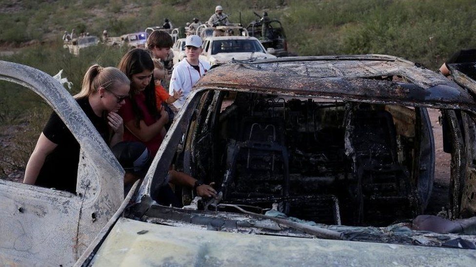 Relatives of slain members of Mexican-American families belonging to Mormon communities observe the burnt wreckage of a vehicle where some of their relatives died