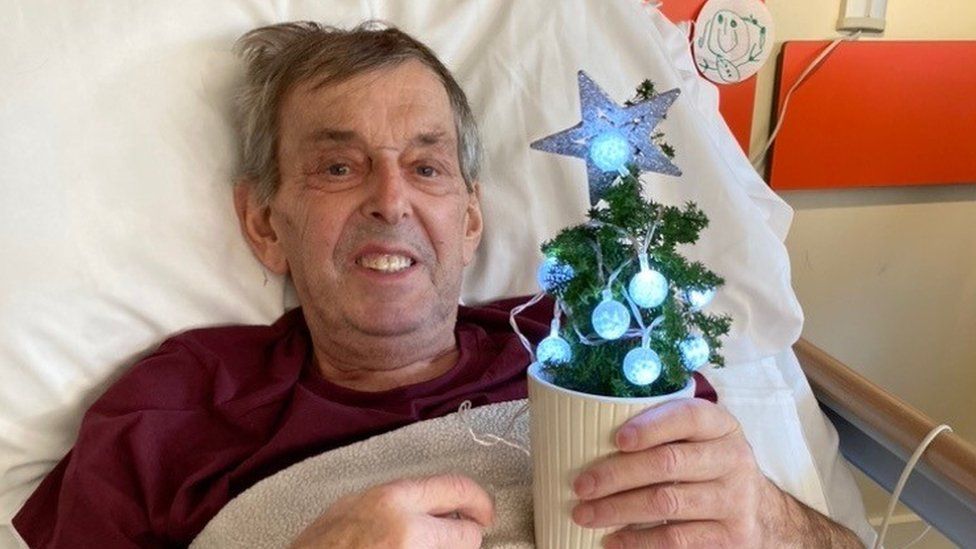 John Hunt holding a miniature Christmas tree at the inpatient ward