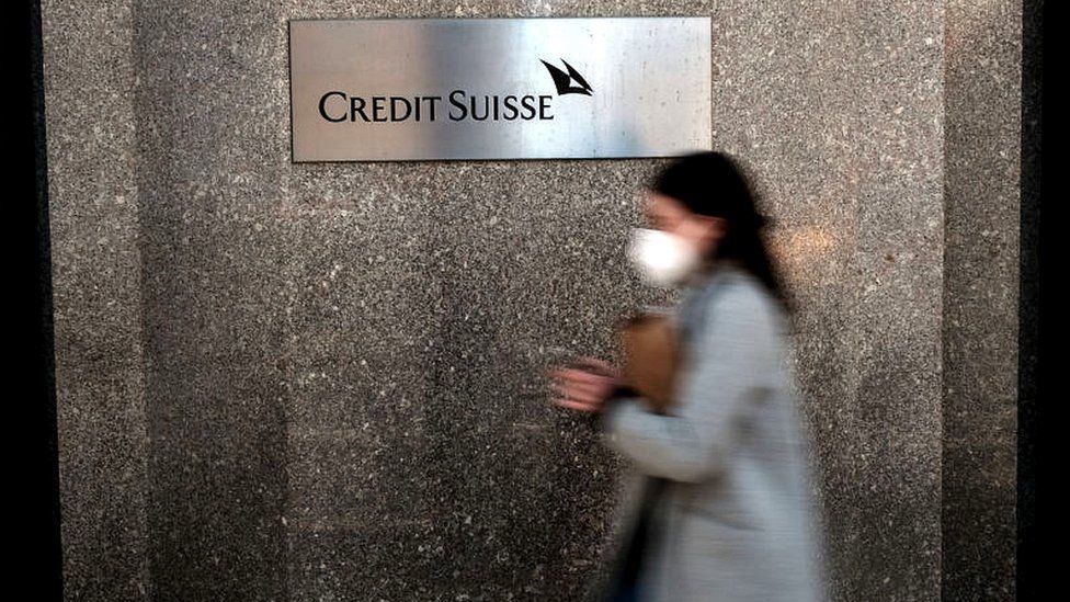 Woman walks past Credit Suisse sign