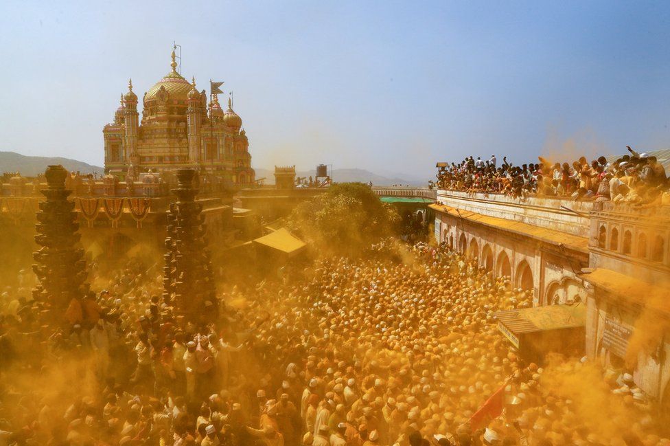 Devotees throw turmeric powder as an offering to the shepherd god Khandoba as others carry a palanquin during 'Somvati Amavasya' at a temple in Jejuri, India, 4 February 2019.