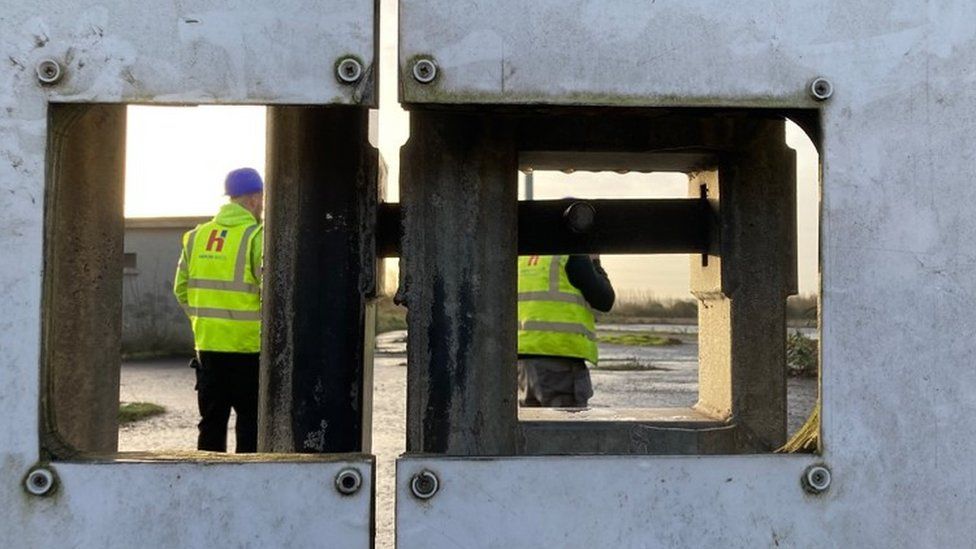 A shot looking through the gates of casement park, showing two workers inside in high-viz jackets