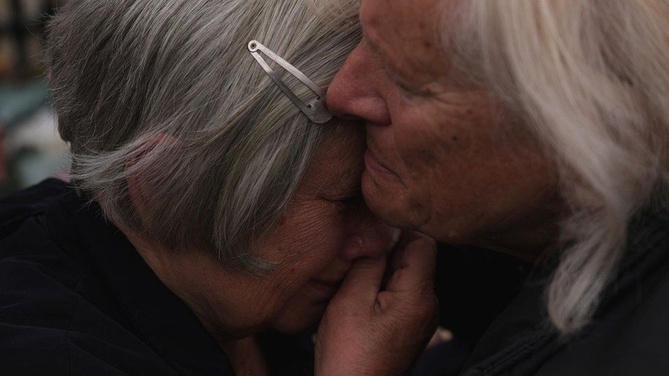 Two women embrace in tears