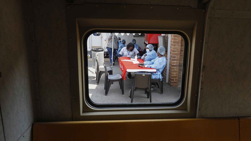 Healthcare workers wait to register people for vaccines outside a Transvaco train