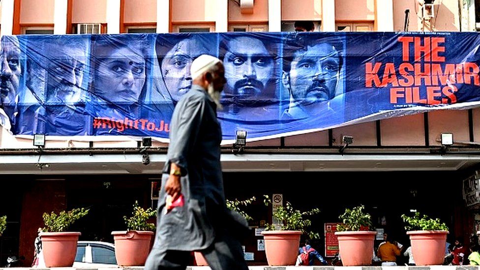 A man walks past a banner of Bollywood movie 'The Kashmir Files' installed outside a cinema hall in the old quarters of Delhi on March 21, 2022