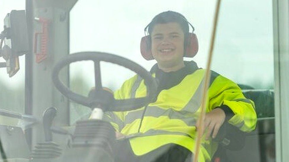 Dominic Jones wearing a high vis jacket in a heavy-duty machine in Norfolk