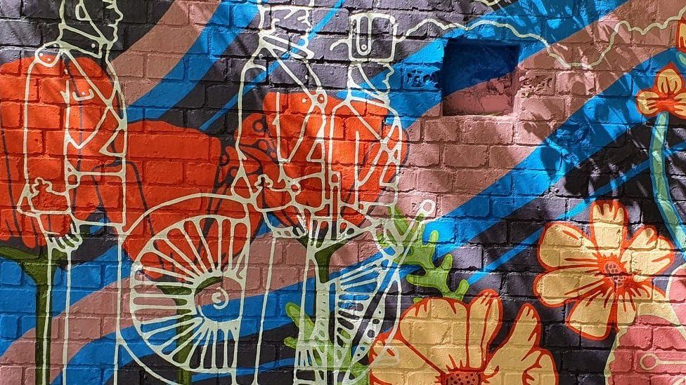 Colourful mural showing three soldiers and a cannon surrounded by huge flowers